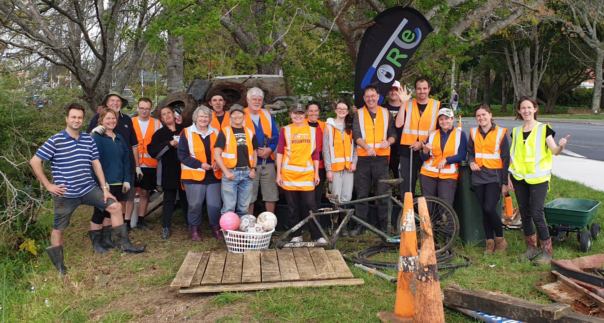 A bunch of Love Whangarei Monthly Clean Ups volunteers pose for a group shot with some of the waste items they rubbish cleared wearing High Vis gear.